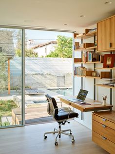 a desk with a laptop on it in front of a sliding glass door that leads to an outside patio