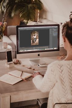 a woman sitting at a desk in front of a computer monitor with photos on it