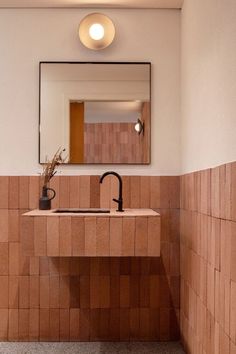 a bathroom with a sink, mirror and tiled walls in the corner that has a vase on it