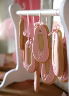 some cookies are hanging from a rack with pink icing and bows on the strings