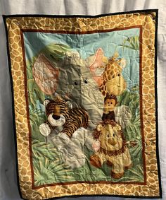 a quilted wall hanging with animals and giraffes on it's side