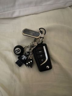 a cell phone keychain with keys attached to it on a white bed sheet