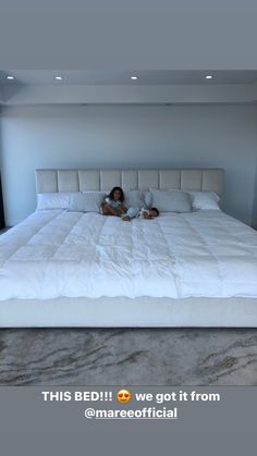 a woman laying on top of a white bed in a room