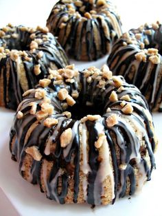 there are six donuts with chocolate icing and nuts on top, sitting on a white plate