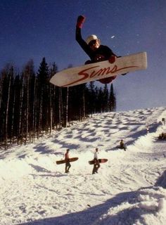 a man flying through the air while riding a snowboard on top of a snow covered slope