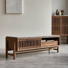 a wooden bench sitting on top of a floor next to a painting and vases