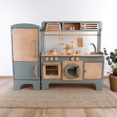 a wooden toy kitchen playset with an oven, sink and stove top on the floor