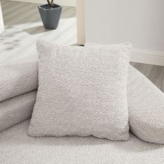 two pillows sitting on top of a bed next to a plant