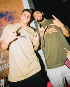 two men standing next to each other giving the peace sign