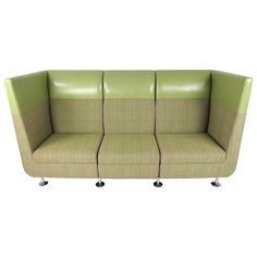 a green and beige couch sitting on top of a white floor