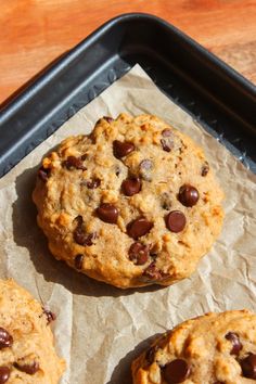 three chocolate chip cookies sitting on top of a pan