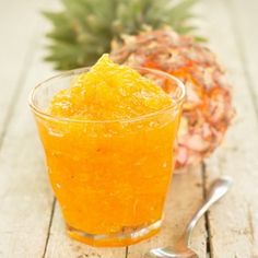 a pineapple sits next to a glass of orange juice