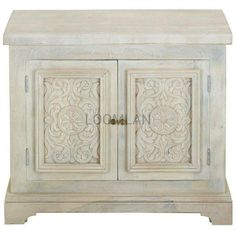 a white cabinet with two doors and carvings on the front, sitting against a white background