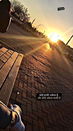 a person sitting on a bench with the sun setting in the back ground behind them