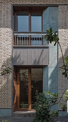 an apartment building with brick walls and wooden balconies on the second floor, surrounded by greenery