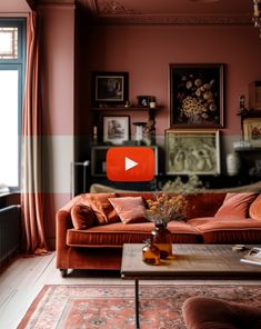 a living room with an orange couch and red curtains on the window sill in front of it