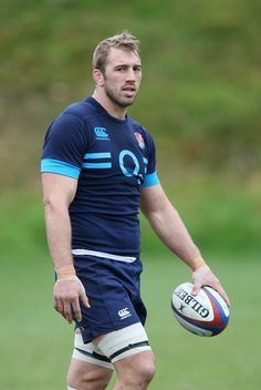 a man holding a rugby ball on top of a field