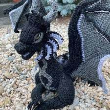 a crocheted dragon sitting on top of gravel