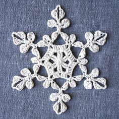 a crocheted snowflake is shown on a blue surface