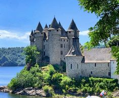 an old castle sitting on top of a small island next to the water and trees