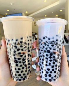 two people holding up cups with black and white designs on them