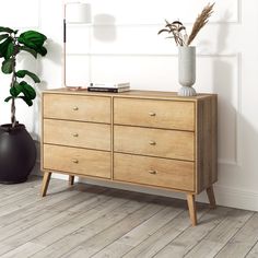 a wooden dresser sitting next to a potted plant on top of a hard wood floor