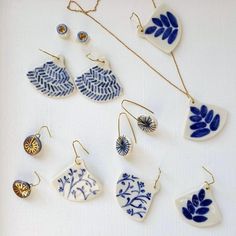 a collection of blue and white porcelain items on a white surface with gold chain necklaces