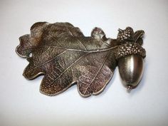 an oak leaf and acorn broochle on a white surface with space for text