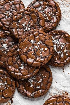 a pile of chocolate cookies with powdered sugar on top and one cookie in the middle