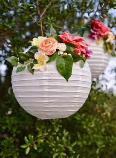 two white paper lanterns with flowers hanging from them