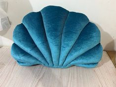 a blue shell shaped pillow sitting on top of a wooden table