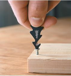 a person is holding a small piece of wood with a knife in it's hand