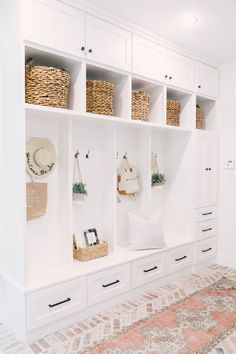 a room with white cabinets and baskets on the wall, along with other items such as bookshelves