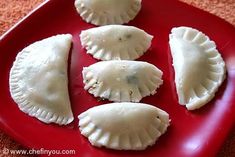 four small dumplings on a red plate