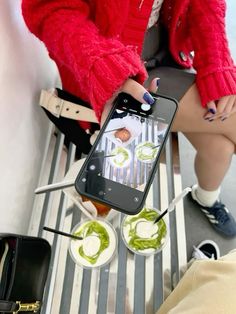 a woman sitting on a bench holding a cell phone with sushi and chopsticks in front of her