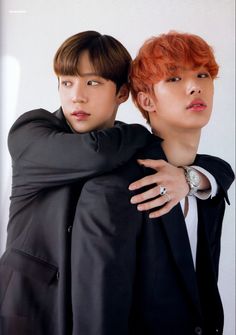 two young men hugging each other in front of a white wall