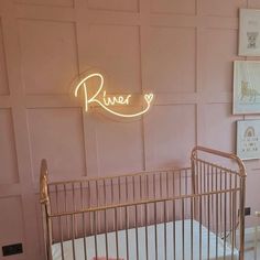 a baby's crib in front of a pink wall with a neon sign above it