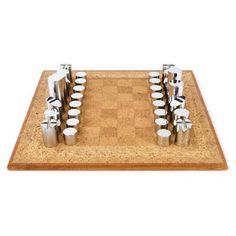 a set of chess pieces sitting on top of a cork board with silver cups around them