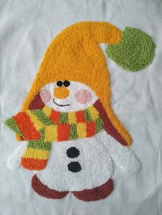 a close up of a snowman with a hat and scarf on top of a white sheet