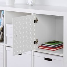 a white cabinet with drawers and a clock on the wall