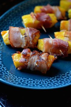 bacon wrapped pineapple skewers on a blue plate