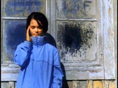 a woman standing in front of a door talking on a cell phone while holding her hand to her ear