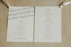 two wedding programs with ribbons tied to them on a wooden table, ready for the ceremony