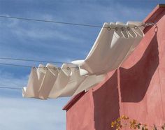 an umbrella is hanging from the side of a pink building with power lines in the background