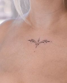 a woman's chest with a small tattoo design on the back of her neck