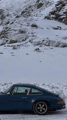 a blue sports car parked in front of a mountain covered in snow and ice,