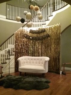 a white couch sitting under a staircase next to a banister and chandelier