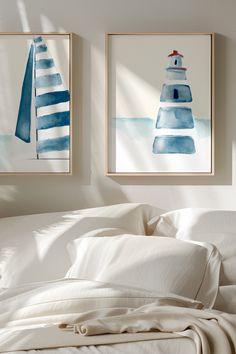 two framed pictures hanging on the wall above a bed with white linens and pillows