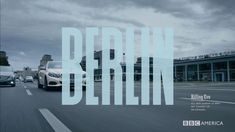 two cars driving down the road in front of a building with large letters that read berlin