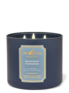 a blue candle that is sitting on a white surface with the words mahogany teakwood in